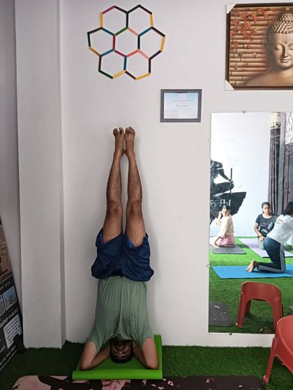 A student practicing a supported headstand against the wall. The wall is a great tool for beginners to get comfortable with being inverted.