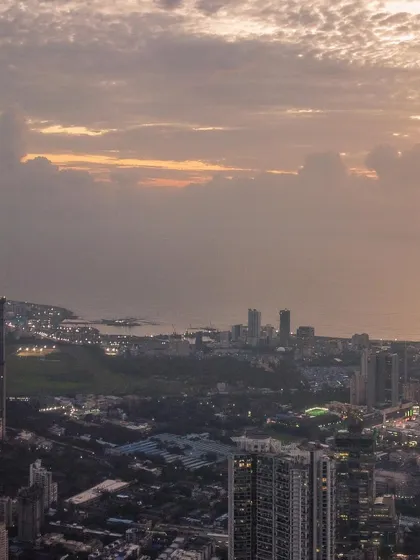 A detailed shot of the Mumbai coastline and Malabar Hill area, seen from a high altitude under a textured sky.