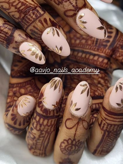 A detailed shot of these elegant bridal nails. The matte nude base provides the perfect canvas for the hand-painted gold foil leaves, creating a sophisticated and timeless design.