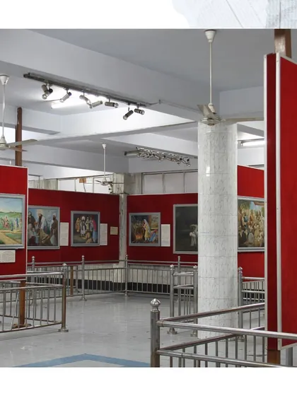 A wide view of an exhibition hall inside the Bhai Mati Das Museum. The displays, featuring history paintings against vibrant red walls, create a distinct visual narrative that I critically examine in my work on Sikh museology.