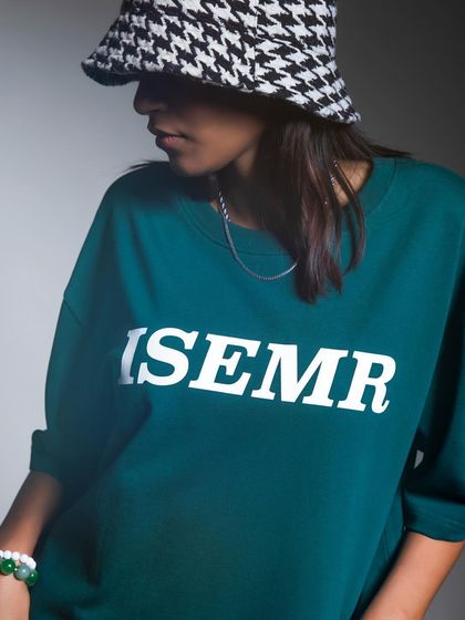 A close-up shot focusing on the accessories used in a streetwear campaign. The houndstooth bucket hat and simple chain necklace add layers and personality to the look.