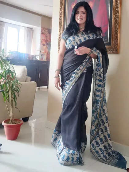 A full-length view of the black and indigo saree, showcasing its elegant fall and the striking printed border.