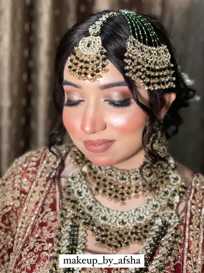 A close-up of another beautiful bride. The contrast between her dark hair, red and gold outfit, and the green jewellery is absolutely striking. The makeup is glamorous with a nude lip to balance the look.