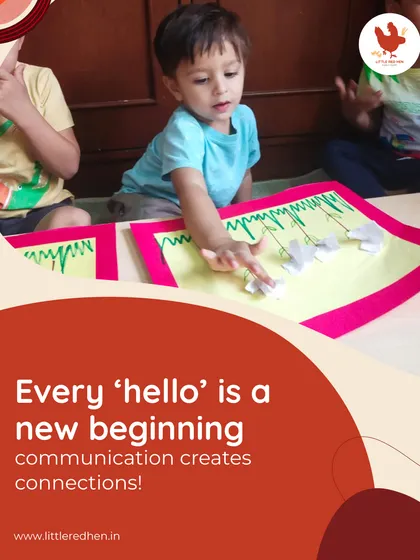 Every 'hello' is a new beginning. A child points to a craft, learning to communicate and connect through shared activities and songs.