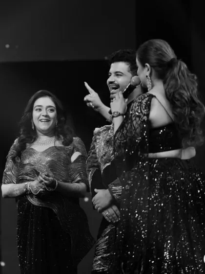 A candid moment of joy on stage. Here you can see the coordinated outfits in action, with the sister of the groom in a metallic draped saree that complements the groom's brother-in-law's embellished bandhgala.