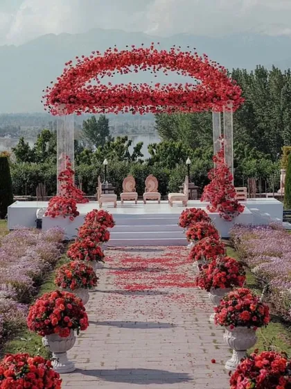 For a bold and passionate statement, we designed this stunning outdoor mandap using thousands of red roses. The circular floral arch creates a dramatic focal point, perfectly framing the couple against a beautiful natural landscape. This is a great example of our custom floral architecture.