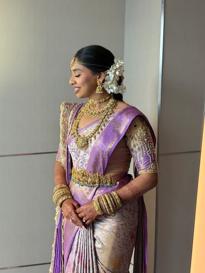 A candid side profile, showing the elegant bridal updo adorned with a cascade of fresh white flowers, a hallmark of South Indian bridal style.