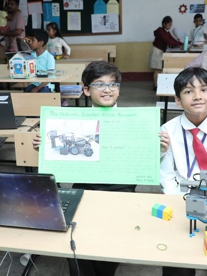 Two students proudly present their robotics project and the poster they created to explain it. Our program encourages not just building but also developing communication and presentation skills.