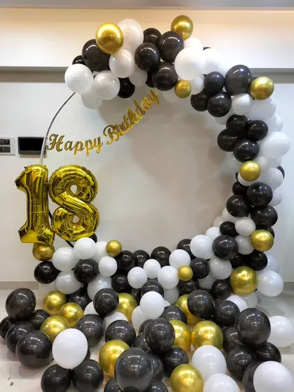A classic and bold 18th birthday ring decoration. The full ring is covered in black, white, and gold balloons, with large '18' foil numbers, creating a perfect photo op for this important milestone.