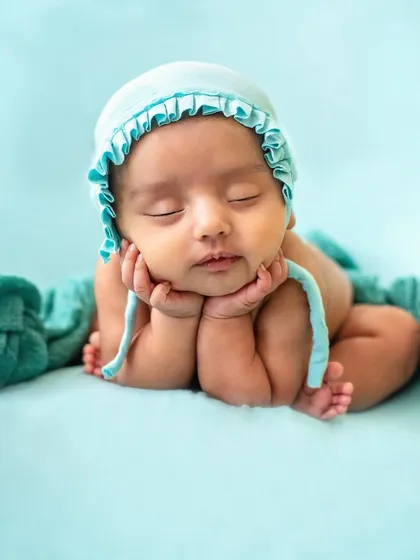 The classic "chin on hands" pose. This highlights the baby's chubby cheeks and peaceful expression, a must-have shot in any newborn gallery.