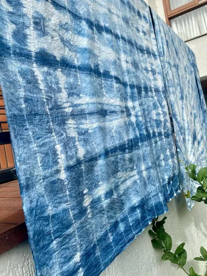 Sunlight filtering through indigo-dyed fabric, highlighting the beautiful, cloud-like patterns. Each piece is a unique work of art, created by the interplay of dye, fabric, and technique.