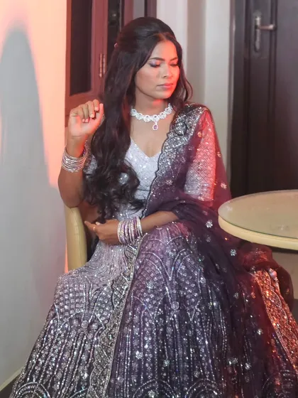 A bride smiling happily in her sparkling reception lehenga. The makeup is glamorous and complements her joyful expression.