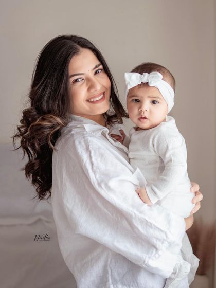 A mother holding her baby girl, both looking at the camera.