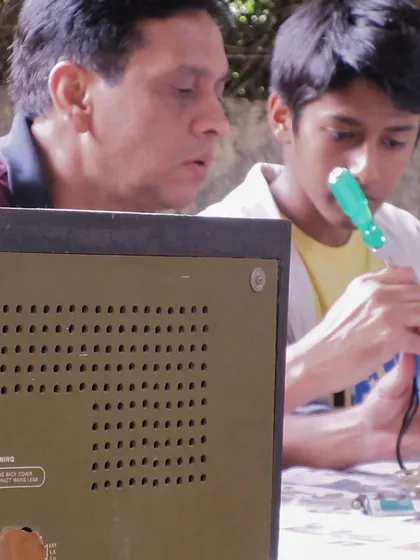 A mentor and student work together on an old television set, learning about its components. Our program encourages intergenerational skill sharing, connecting experienced tinkerers with the next generation of fixers.