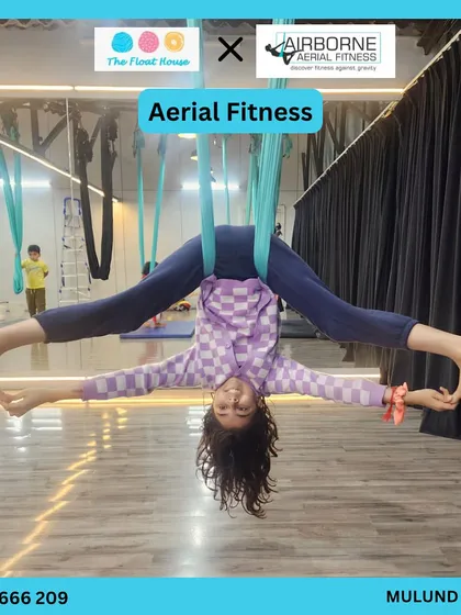 A young student mastering an inverted pose during an aerial fitness class, showcasing her strength and balance.