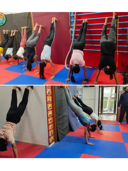 We focus on progressive strength building, as seen in this handstand practice session. Students use the wall for support to develop shoulder stability and balance, a foundational skill for more advanced yoga and gymnastic movements.