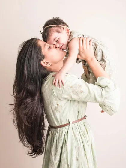 A kiss filled with pure adoration. This beautiful shot of a mother lifting her daughter up is overflowing with joy and affection.
