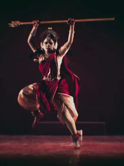 A dancer in a dynamic, powerful pose, holding a staff. This moment from "Shrishti Stithi Laya" captures the fierce, warrior aspect of the divine feminine energy.
