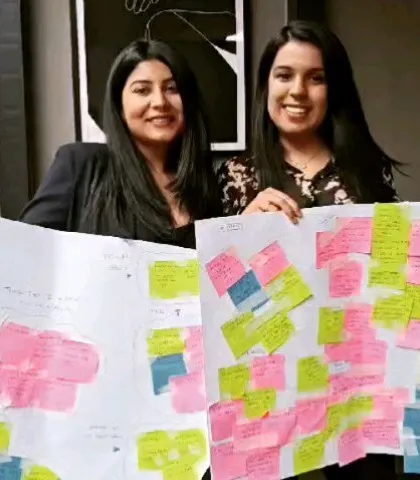 Two participants hold up their "Design Your Life for Happiness" charts, a tool created during our workshop to help build a more joyful life.