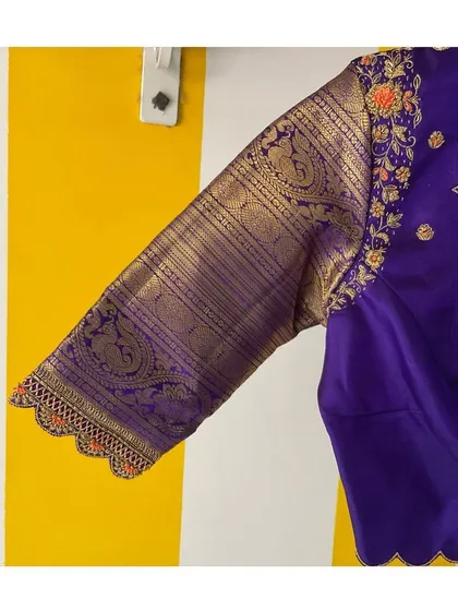 Elegance never goes out of fashion. This purple blouse features a Kanjeevaram border on the sleeve, enhanced with delicate hand embroidery.