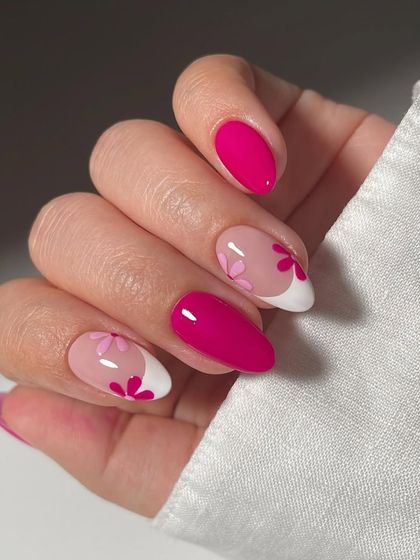 A modern and romantic floral design. This set combines solid magenta nails with negative space art, featuring pink flowers on a modern French tip for a chic and stylish look.