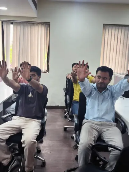 A close-up of employees practicing a seated spinal twist. This gentle movement helps to increase spinal mobility and relieve lower back tension, a common issue in corporate environments.