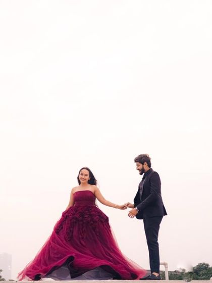 A sweet, candid moment between the couple. The flowing tulle of the maroon gown adds a sense of movement and romance to the shot.
