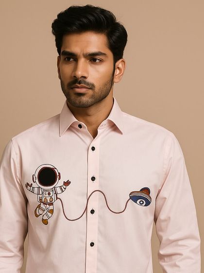 A portrait view that brings the whimsical astronaut embroidery into focus. The light pink fabric and black buttons create a modern color combination.