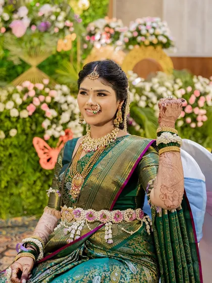 A smiling portrait of the mom-to-be. Her floral kamarbandh and bajuband are custom-designed with pink flowers to match the border of her saree.