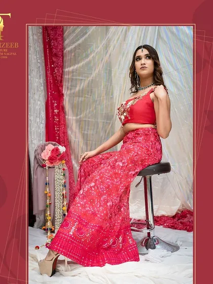 A seated pose showcasing the beautiful print and embroidery of our red sharara set.