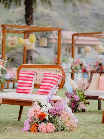 A vibrant seating area from the 'Sunny Sway Soirée', with lush florals and colorful striped cushions.