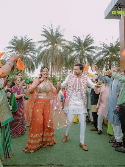 The couple's grand entry at their Haldi, dancing through a tunnel of guests waving orange flags.