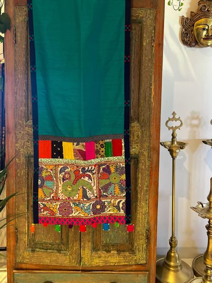 A green silk runner finished with a vintage cross-stitch embroidery trim and a colorful patchwork border. This piece is a beautiful example of mixing different craft techniques.