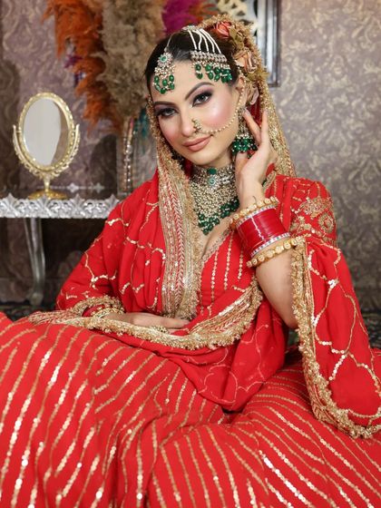 A seated pose showcasing the full bridal look, from the outfit to the jewelry and henna.