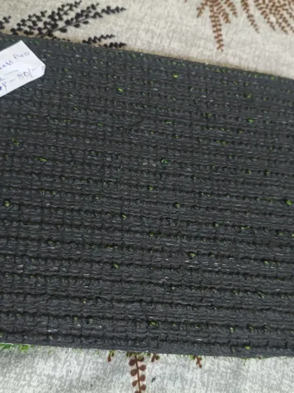 A clear view of a standard turf backing with drainage perforations. These holes are essential for outdoor installations to allow rainwater to drain through.