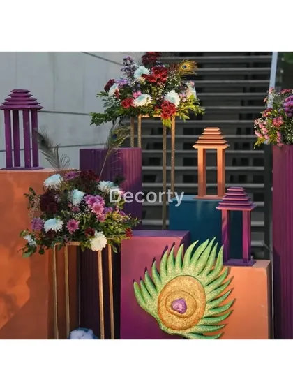 Colorful plinths decorated with floral arrangements and peacock feather motifs, adding to the vibrant Vrindavan decor.