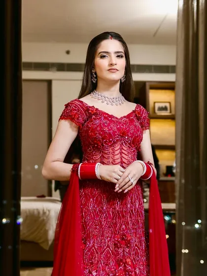A powerful and poised portrait. Her makeup is clean and elegant, with a focus on defined features that complement her diamond jewelry and stunning red outfit.