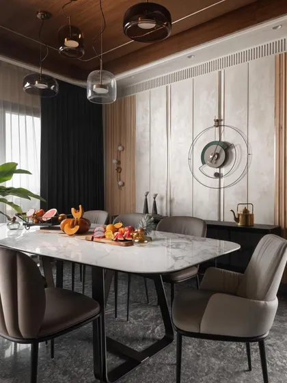 The dining area is defined by a curved ceiling detail and a sophisticated mix of materials. A marble-topped table is surrounded by comfortable upholstered chairs, set against a backdrop of textured wall panels and wood fluting.