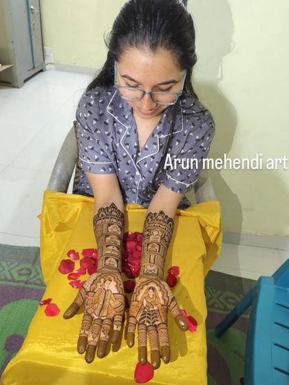 A bride admiring her freshly done mehendi, which tells the story of her wedding through intricate portraits and scenes.