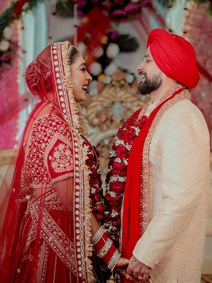 The happy couple. Her classic red bridal makeup stands out beautifully against the festive backdrop.