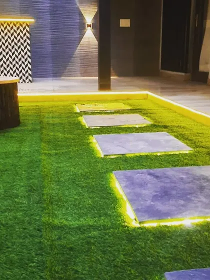 A close-up of the backlit stone pathway, where the light beautifully outlines each stone on the artificial grass.