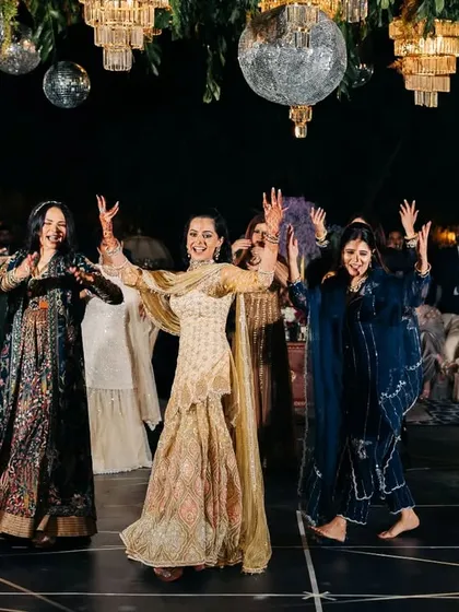 The bride joins her family on stage for a joyous group dance. The disco balls and chandeliers at Suryagarh created the perfect backdrop for this energetic performance, learned entirely online.