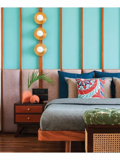 Color and texture bring this bedroom to life. Teal blue walls with wooden rafters are paired with a taupe fabric headboard and a teak wood bed. The vibrant combination creates a contemporary yet warm space that is full of personality.