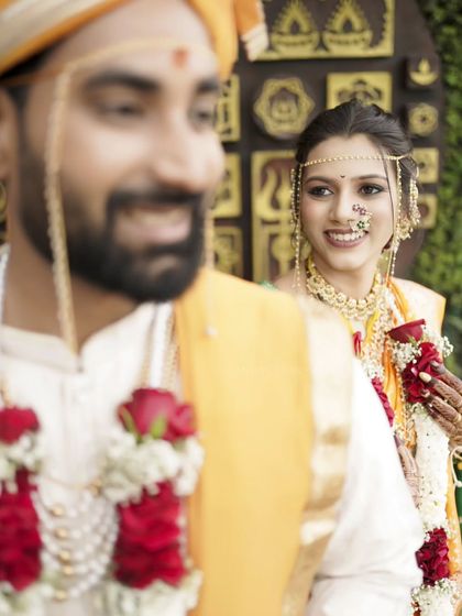 A creative shot during the 'Varmala' ceremony, capturing the bride's loving gaze from behind the groom.