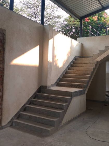 The interior staircase at the Artist Residency. The soft texture of the natural lime plaster on the walls provides a warm, tactile contrast to the sharp, industrial lines of the external steel structure, creating a balanced interior environment.