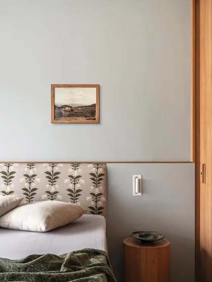A close-up of the master bedroom in Apartment 3201, showing the delicate floral pattern of the headboard against the cool blue wall. This detail highlights our approach of layering soft patterns and textures to create a warm, inviting atmosphere.
