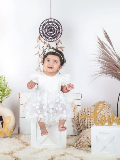 This little angel is sitting pretty in her white dress in our bright and airy lifestyle setup.