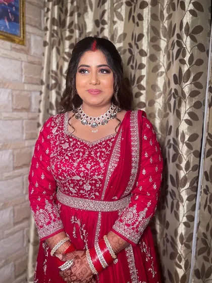 A beautiful reception bride in a vibrant red anarkali. The makeup is glamorous with a smokey eye and a nude lip.