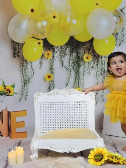 This candid shot captures a playful moment during a sunflower themed first birthday, with the little one sticking her tongue out, full of personality.
