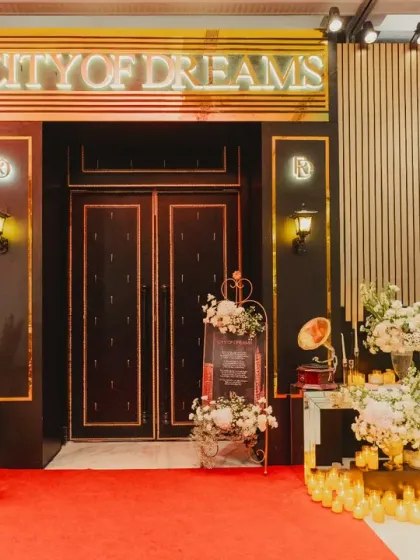 The grand entrance to the 'City of Dreams' party, complete with a red carpet, neon sign, and elegant floral arrangements.